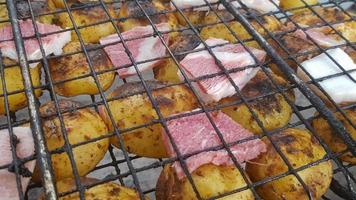 Grilled potatoes with bacon, whole baked on the barbecue grill. Selective focus. Whole small potatoes with bacon bits and grilled. Baked potatoes with grilled bacon. photo