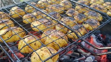 Grilled potatoes with bacon, whole baked on the barbecue grill. Selective focus. Whole small potatoes with bacon bits and grilled. Baked potatoes with grilled bacon. photo