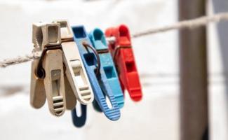 Plastic clothespins hang in a row on the rope. Rope outdoors, on a blurred background in a sunny garden. Clothesline on the street. Clothespins. photo