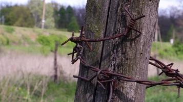 Old wooden fence with rusty barbed wire. A fence next to a rural road. Vintage look. A wooden post around the perimeter of the pasture fence. photo