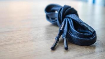 una foto de sujeto de cordones planos azul oscuro con puntas finas para zapatos enrollados y aislados sobre un fondo de madera. accesorio elegante.