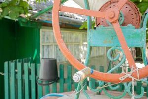 An old water well with a bucket in the garden, a metal handle for lifting water from the ground. Village well under the roof with a rope. Retro well in the countryside. photo