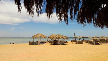 costa del mar con sombrillas de paja en una playa de arena. paisaje marino en la playa al final de la temporada navideña. un gran lugar para relajarse en el mar rojo en sharm el sheikh, egipto. foto