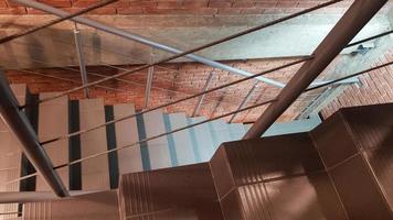 Red brick building with a modern staircase in a loft style with metal railing. Stairs adorn the building. Modern stairwell. Steel railing. Staircase in perspective. photo