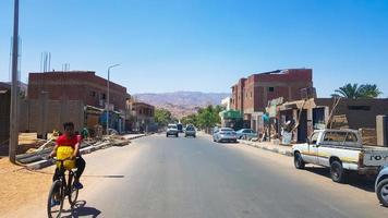 Egipto, Dahab - 20 de junio de 2019. Un árabe en bicicleta por una de las calles de Dahab. calle del desierto. edificios residenciales egipcios. la ciudad de dahab. foto