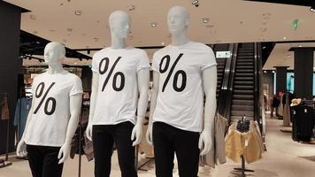 Mannequins wearing white T-shirts with a percent sale sign in a shopping mall Promotion, advertising, shopping and black friday concept. Ukraine, Kiev - September 1, 2020. photo
