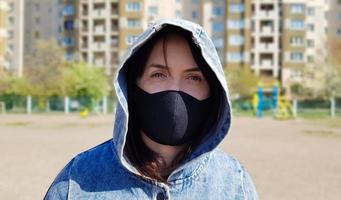 Portrait of a woman in a protective black mask outdoors near an old broken wall. Coronavirus and air pollution concept. A girl wears a protective mask to protect against a pandemic. photo