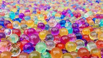 Lots of different colored hydrogel balls. Set of multicolored orbis. Crystal water beads for games. Helium balloons. Can be used as a background. Polymer gel Silica gel. photo