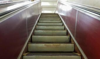 una escalera mecánica vacía sin gente en la estación de metro de la línea roja del metro de kiev. Cerca de los escalones de metal de una escalera mecánica que se mueve de abajo hacia arriba foto