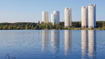 Ukraine, Kiev - May 25, 2020. Beautiful new residential complex with five high-rise buildings on a lake with blue water. Reflection in the water of high-rise buildings. Editorial photo.