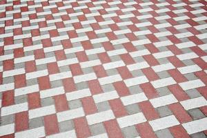 Concrete or paved newly laid gray and red paving slabs or stones for floors or walkways. Concrete paving slabs in the backyard or road paving. Garden brick path in the courtyard on a sandy foundation. photo