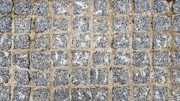 surface paved with black road tiles. top view. Granite paving stones on a sidewalk or pavement textured paving background. Close up top view.