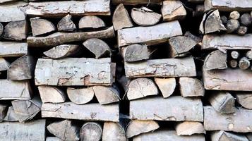 A neatly folded log of chopped wood. The fire is melting. Firewood stacked on top of each other. Firewood is collected for heating in cold weather. Background texture of stacked dry firewoods