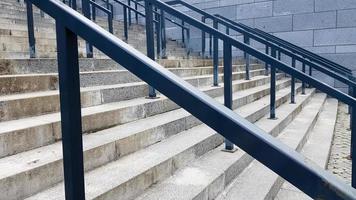 External multi-stage stone staircase. There are a lot of stairs and railings made of metal. Many steps in an urban environment, symbolic abstract background.