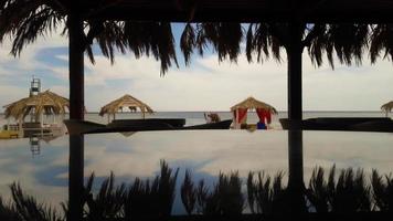 Round glass table, which depicts palm trees, sea and sky. Beautiful view of the beach in a tourist town. Summer bar on the Red Sea. Pergolas with sun loungers to protect from the sun. photo