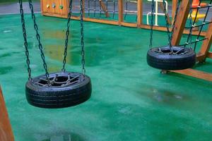 A courtyard of high-rise buildings with a modern and large playground made of wood and plastic on a rainy summer day without people. Empty outdoor playground. A place for children's games and sports. photo