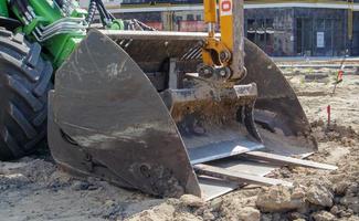 Two small excavators on a large construction site. Bright green on wheels and yellow on tracks. Earthworks and construction. Shovel excavator. Mini loaders. Ukraine, Kiev - August 28, 2021. photo