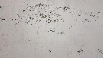 old shabby wall with cracks and chips with whitewash and exfoliated plaster, putty. Vintage gray textured putty on the wall. Rough grunge wall background. photo