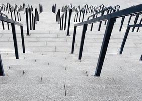 External multi-stage stone staircase. There are a lot of stairs and railings made of metal. Many steps in an urban environment, symbolic abstract background. photo