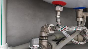 Connection of water supply, hot and cold water to the boiler. Hose for hot and cold water in the bathroom. Plumbing connections for a domestic electric water heater.