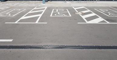 International handicap symbol in a parking lot of a shopping center. The space is clearly indicated on both sides by additional white diagonal stripes photo