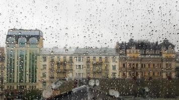 ventana mojada con gotas en el fondo de la ciudad otoñal en tiempo nublado. vista desde la ventana bajo la lluvia. Gota de agua sobre la ventana de vidrio durante la lluvia con fondo borroso de la escena de la ciudad foto