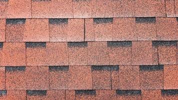 Close up view on Asphalt Roofing Red Shingles Background. Roof Bitumen Shingles - Roofing Construction, Roofing Repair. Red Shingles on the Roof of the House. Background of Red Shingles photo