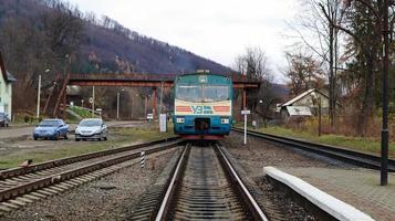 Ucrania, Yaremche - 20 de noviembre de 2019. Tren en la estación sobre un fondo de montañas. vagones de ferrocarril únicos en el andén de la ciudad de yaremche. Antiguo tren de pasajeros diesel. estación de ferrocarril. foto