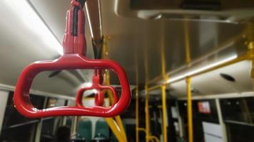 Red hanging handrail on the ceiling for standing passengers in transport. Modern suburban and urban public transport. Empty bus. photo