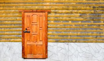 Old wooden door of the house. Minimalist wooden yellow house outside with entrance door. Facade of rural house outdoors with copy space. photo