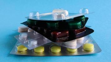 Los paquetes de píldoras de diversas formas y colores se apilan sobre un fondo azul. Las cápsulas están empaquetadas en blísteres. diferentes medicamentos. tratamiento de drogas. foto de salud. copie el espacio.