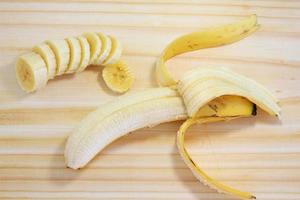 Plátano pelado sobre madera junto a rodajas de plátano foto