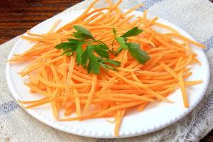 Fresh raw carrot spiralized spaghetti on white plate on rustic wooden table. Concept of healthy food photo