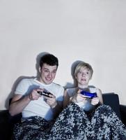 pareja joven jugando videojuegos cómodamente envuelto en una manta. foto