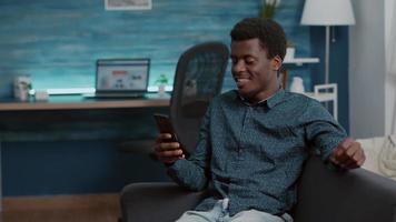 Auténtico hombre afroamericano en videollamada de comunicación virtual usando su teléfono para hablar con familiares o compañeros de trabajo video