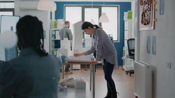 Woman architect designing blueprints plans with building model and maquette on table video