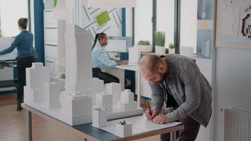 man architect maakt aantekeningen over blauwdrukken plan om bouwstructuur en model te ontwerpen video