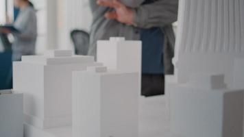 primo piano dell'uomo che analizza il modello di edificio con la donna che utilizza il piano dei progetti sul tavolo video