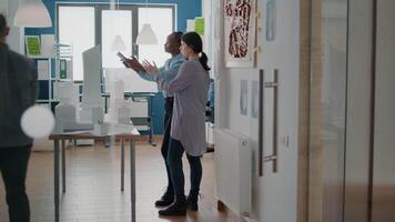 Team of diverse colleagues working with digital tablet on building model video