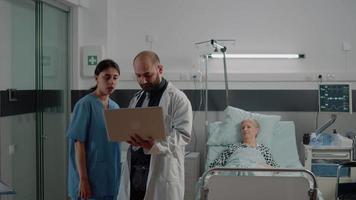 Doctor with laptop discussing with nurse before consultation video