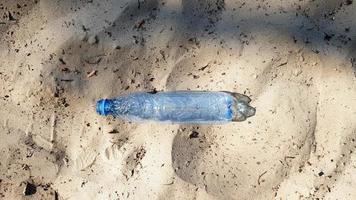 la botella es de plástico. ecología, contaminación plástica. contaminación de los océanos. plástico en la arena. basura en el concepto de playa. contaminación artificial y cartel. semana de promoción mundial. limpiamos el mundo. foto