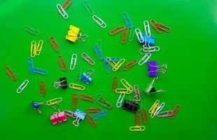 pile of paper clips isolated on green background, documents, office supplies concept, dirty office desk. Empty place for writing and text. Top view, layout. flat lay