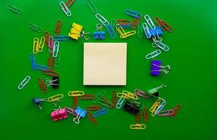 pile of paper clips isolated on green background, documents, office supplies concept, dirty office desk. Empty place for writing and text. Top view, layout. flat lay photo