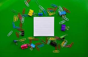 pile of paper clips isolated on green background, documents, office supplies concept, dirty office desk. Empty place for writing and text. Top view, layout. flat lay photo