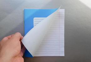 Design concept - Top view of a high quality male hand leafing through a sheet of blue striped notebook. Top view, copy space, flat lay photo