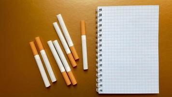 Notebook with cigarettes on top on a gold background photo