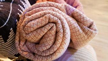 Knitted and warm blankets are folded and laid in a wicker basket near the fireplace. Cozy interior in the house. Details of a modern cozy interior photo