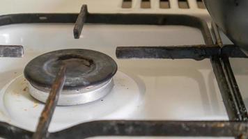 Estufa de gas sucia en la cocina para cocinar con manchas de aceite vegetal y restos de comida quemados en la superficie, primer plano. enfoque selectivo. Encimera de gas engrasada en la cocina.