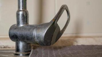 una vieja válvula de una sola palanca con una fuga. Mezclador monomando de lavabo cromado con agua corriente en el lavabo. foto