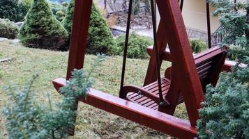 A backyard swing is ideal for relaxing. Garden old wooden swing in the backyard of a rural house. photo